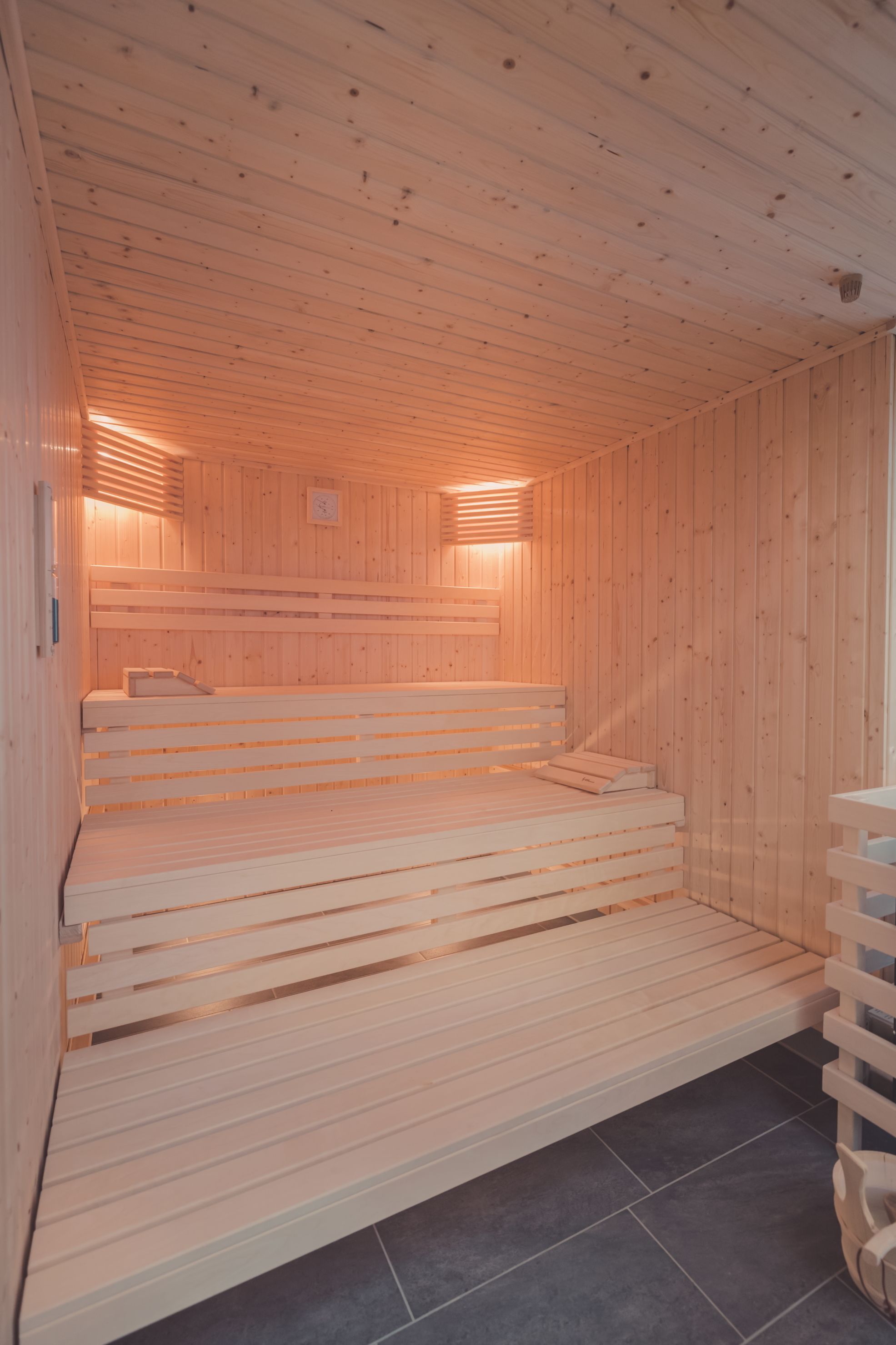A sauna with wooden benches and a sloped floor leading to a lower level.
