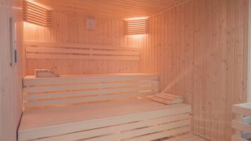 A sauna with wooden benches and a sloped floor leading to a lower level.