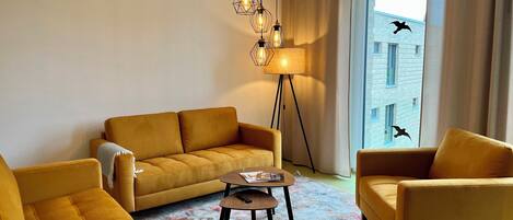 Een moderne woonkamer met een bank, fauteuils, een salontafel en een vloerlamp.