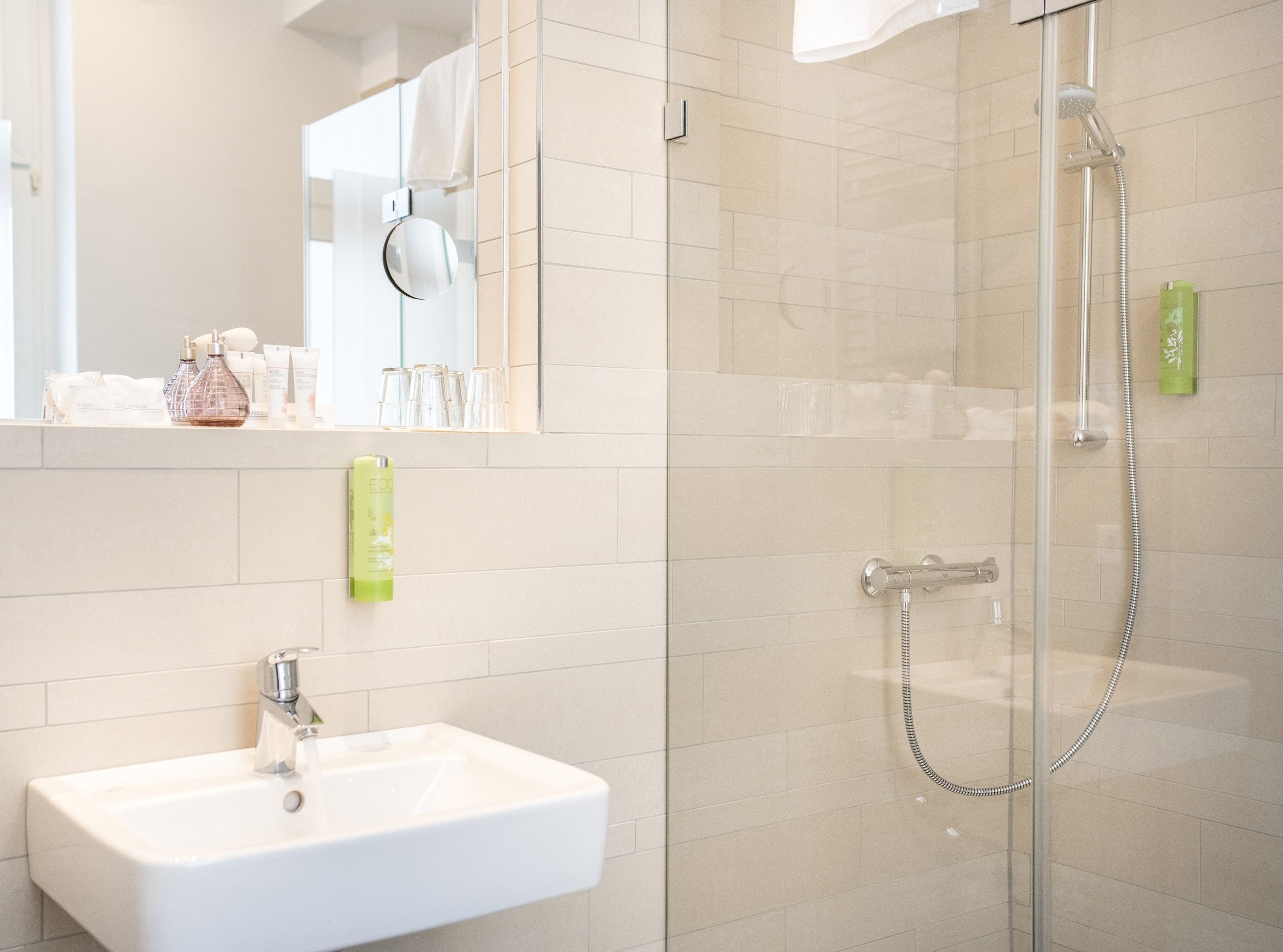 Un baño moderno con cabina de ducha de vidrio, lavamanos y espejo.