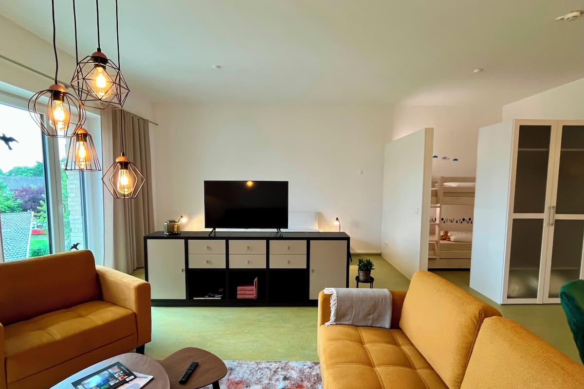 Ein modernes Wohnzimmer mit einer Couch, einem Couchtisch und einem Fernseher auf einem Schrank.