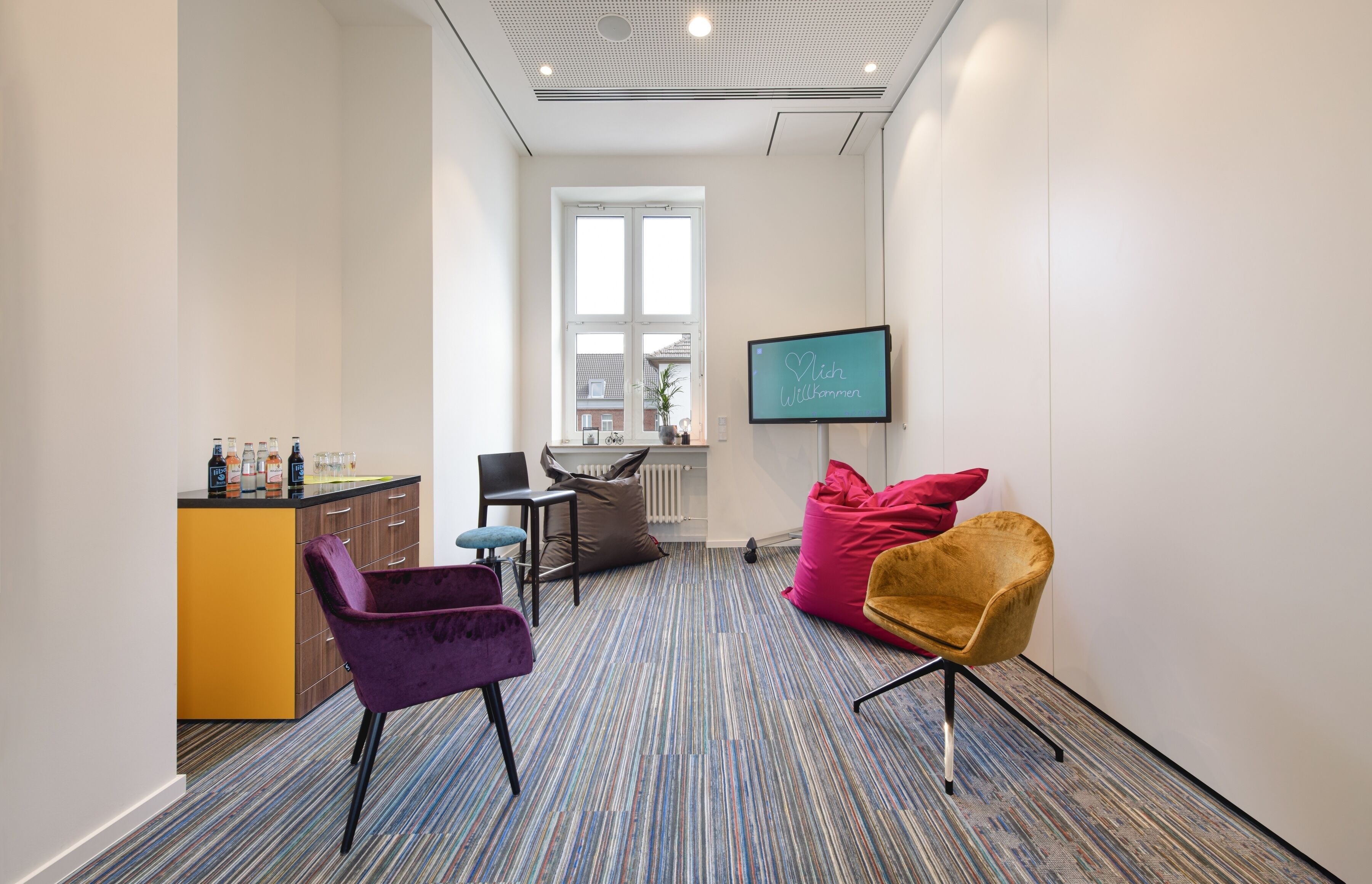 A modern office space with a kitchenette, a large window, and a TV displaying 'Wish Fulfilled'.