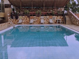 Una piscina con suelo de baldosas y sillas de descanso.