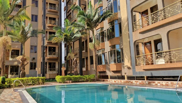 Une piscine entourée de palmiers et un immeuble à plusieurs étages doté de balcons.
