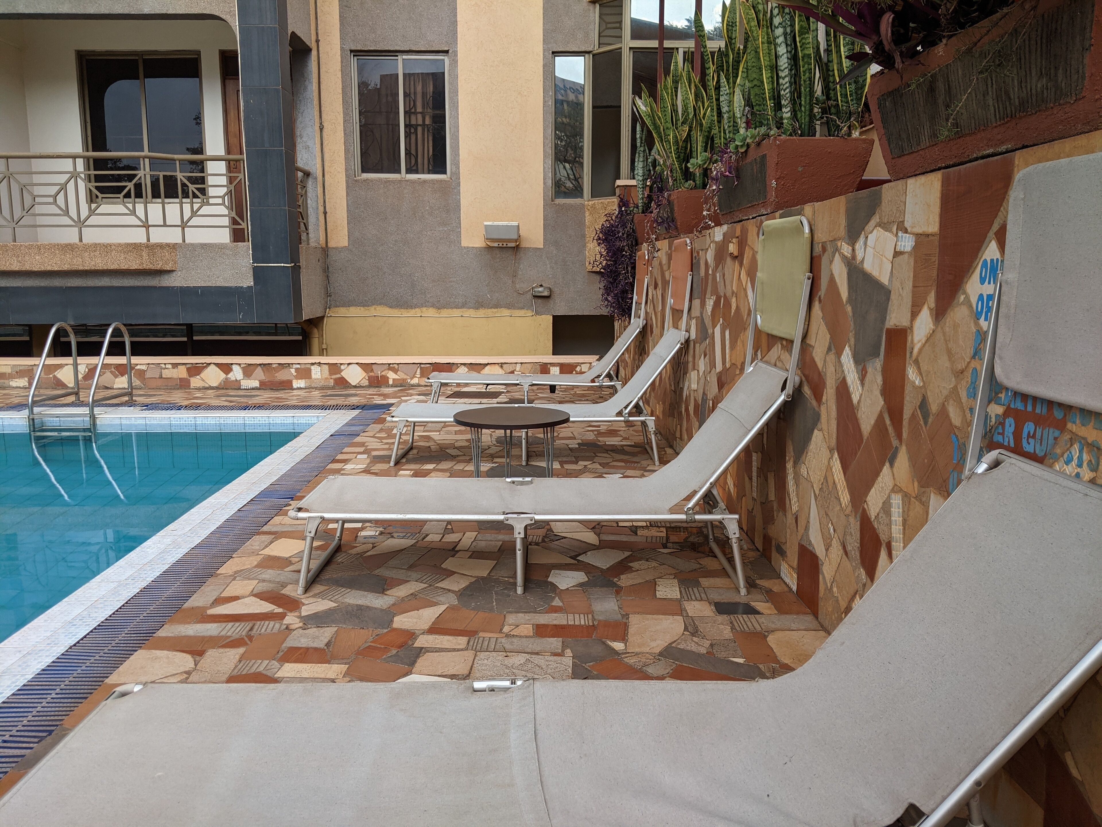A pool area with lounge chairs and a tiled floor.