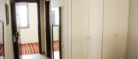Habitación de hotel con un armario grande, una puerta que da a un pasillo y una alfombra a rayas.