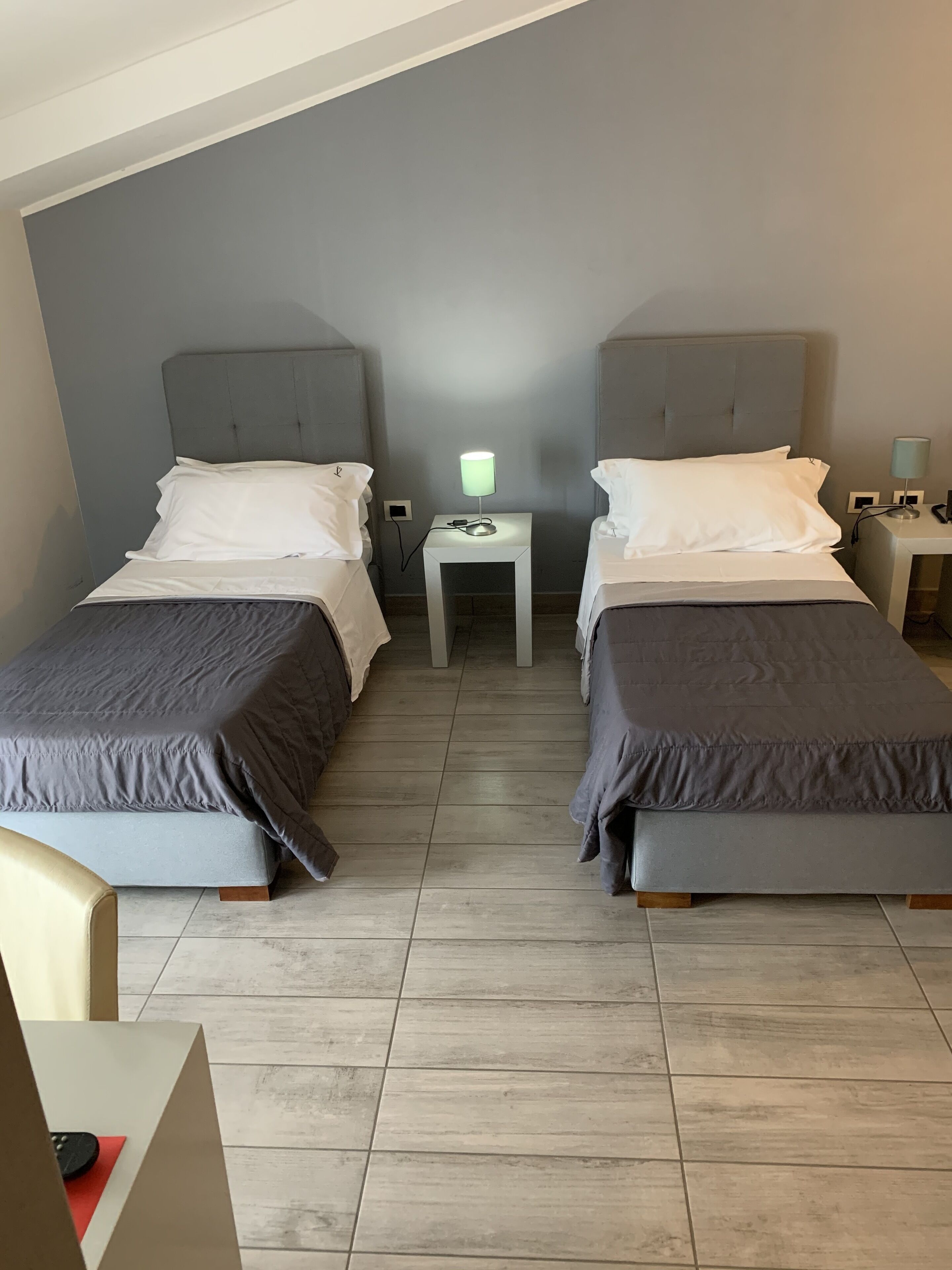 Un dormitorio con dos camas individuales, una mesita de noche con lámpara y una pequeña mesa.