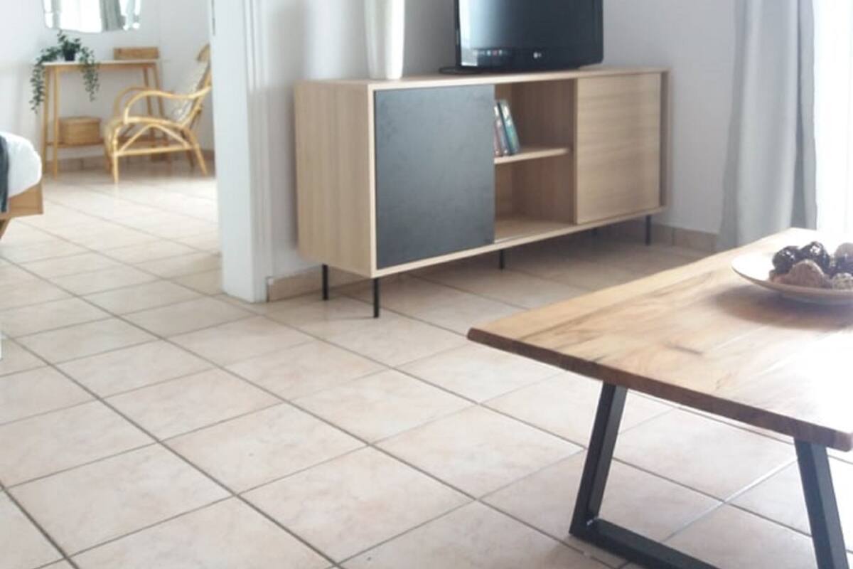 A modern living room with a TV on a wooden cabinet, a dining table, and a plant.