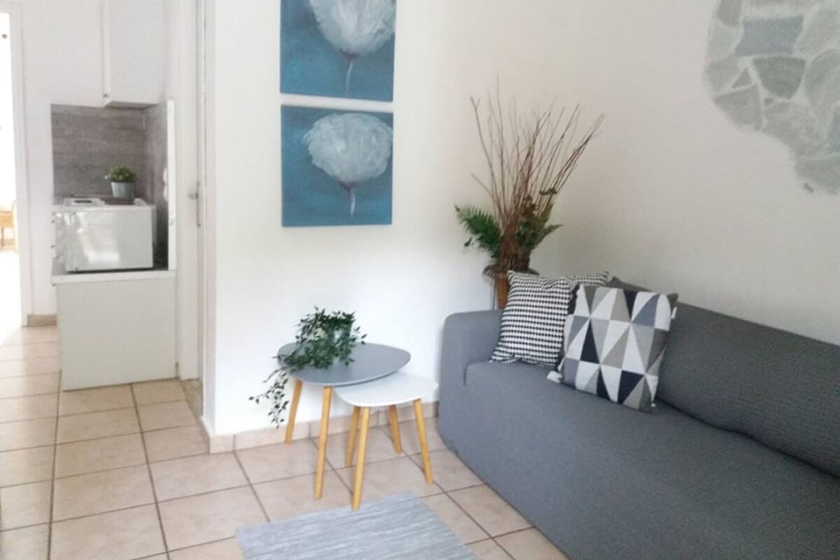 A modern living room with a grey sofa, a small round table, and two wall-mounted paintings.