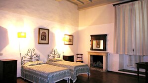 A room with two beds, a fireplace, and a large window with curtains. - Villa Senni (Scarperia e San Piero)