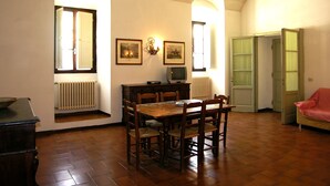 A dining area with a wooden table and chairs, a television, and framed pictures on the wall. - Villa Senni (Scarperia e San Piero)