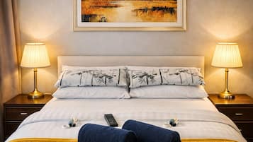 Habitación de hotel con una cama, dos lámparas de noche, un cuadro sobre la cama y un control remoto en la cama.