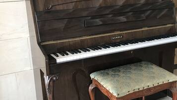 Un pianoforte a coda con una panca, appoggiato su una parete piastrellata.