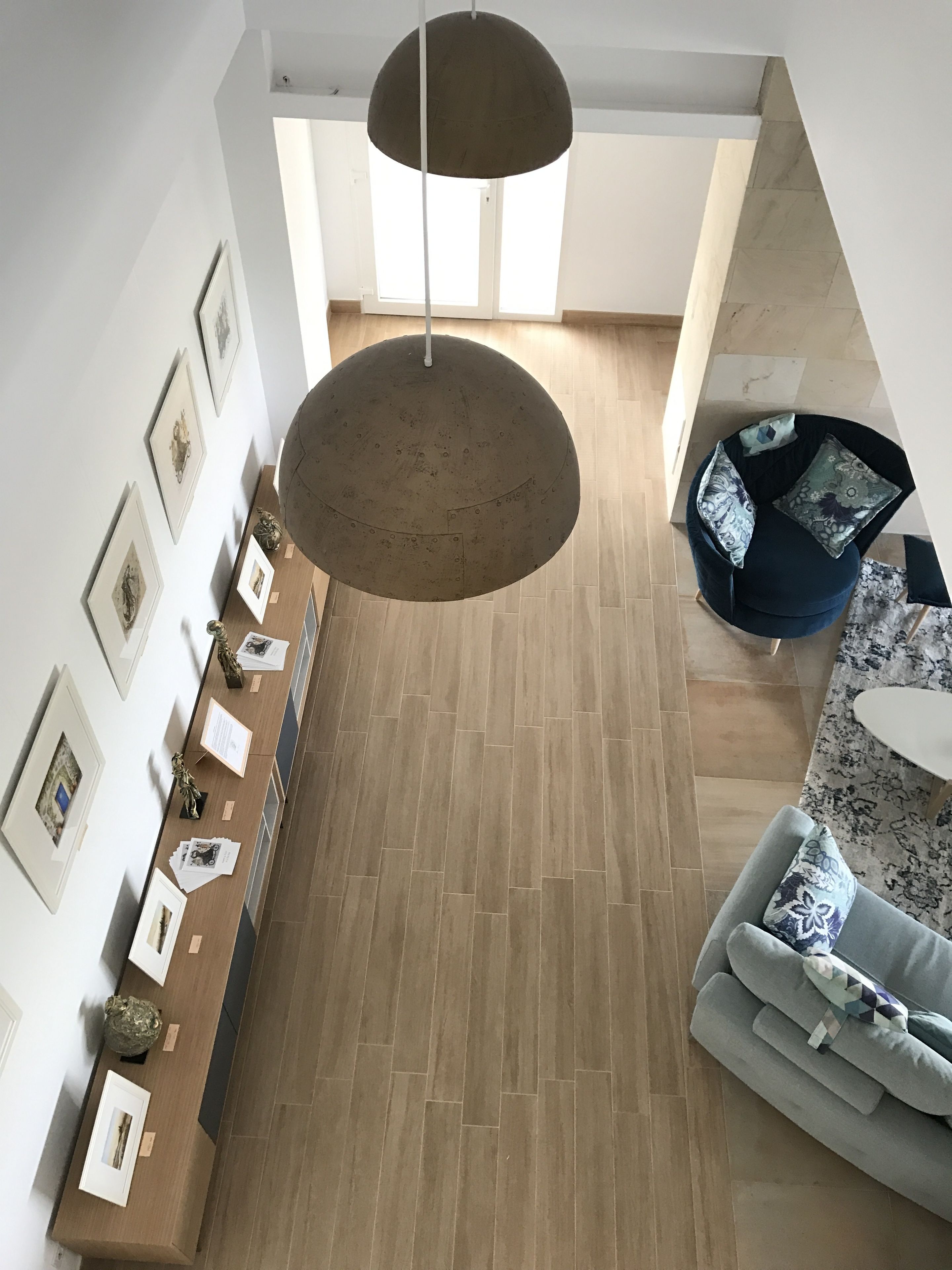 Una habitación amplia con piso de madera, un área de estar con sofá y una mesa redonda, y una recepción con cuadros enmarcados y un letrero.
