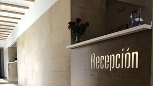 Zona de recepción con un cartel que dice "Recepción" y un florero con rosas rojas en una estantería.