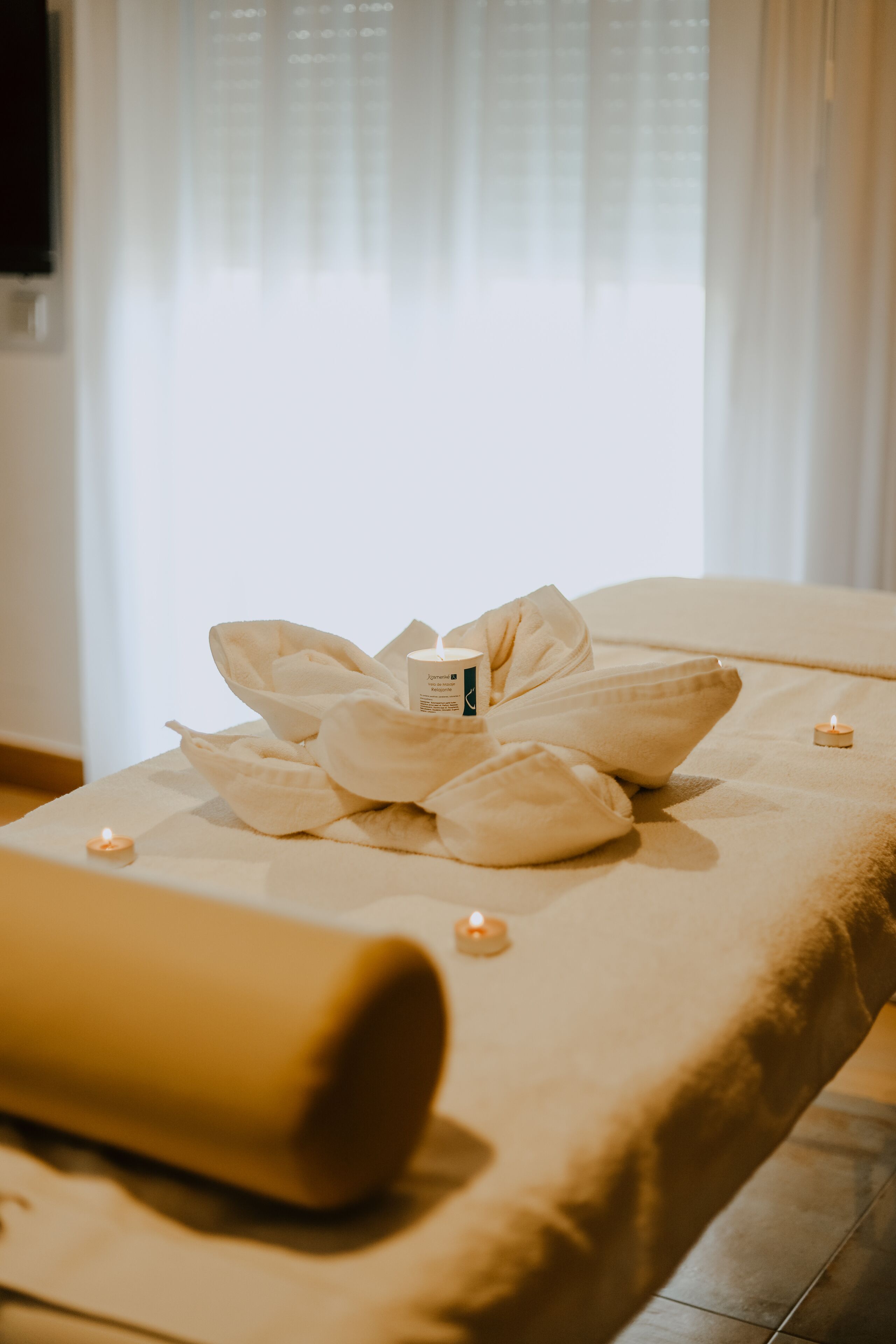 Cama de spa con toallas, velas y una botella de loción.