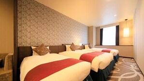 A hotel room with three beds, a patterned wall, a large window, and a carpeted floor.