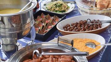 Una mesa de buffet con diversos alimentos, como frijoles, ensaladas y pan.