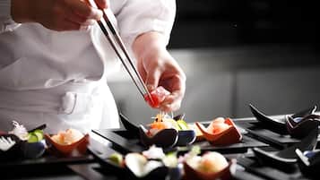 A chef using chopsticks to pick up a piece of food from a dish.