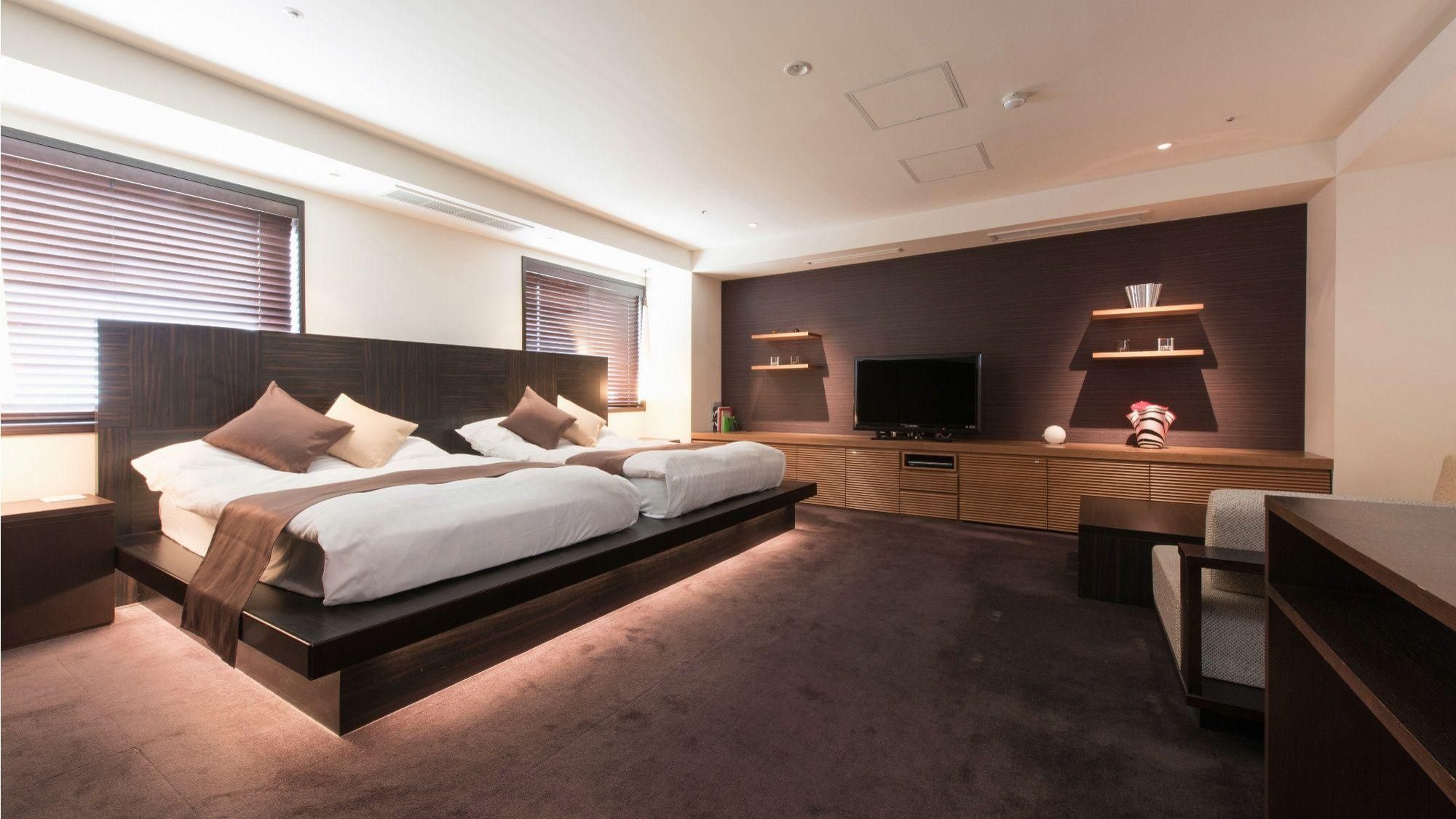Een moderne hotelkamer met een groot bed, een flatscreen televisie, inbouwkasten en een bureau.