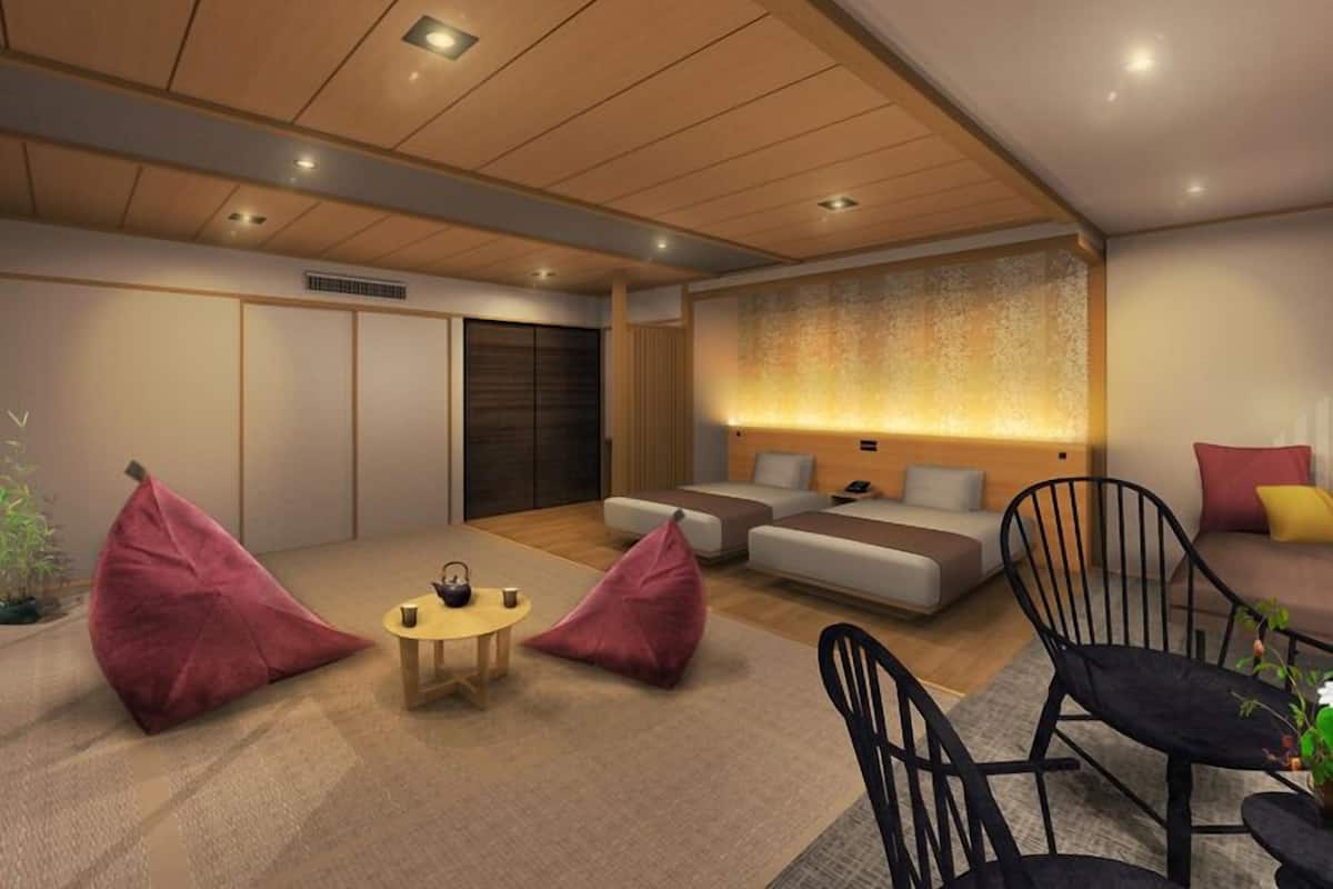 Moderni hotellihuone, jossa on sohvaryhmä, pieni pyöreä pöytä teekannuineen sekä kaksi papupussia.