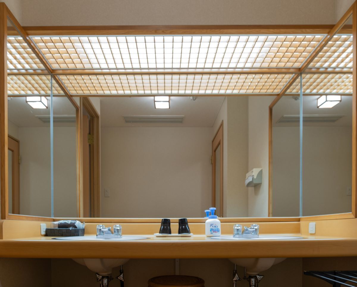 A bathroom with a large mirror, a sink, and a towel rack.