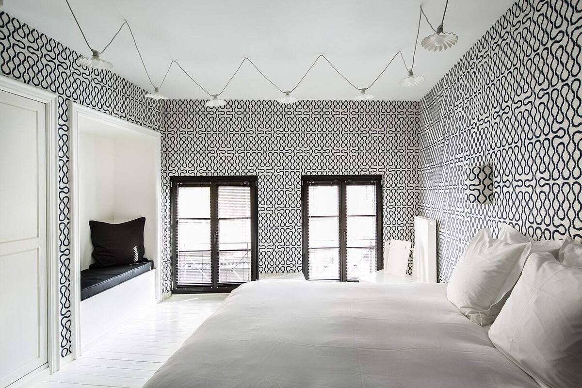 A bedroom with a large bed, two doors, and patterned walls.
