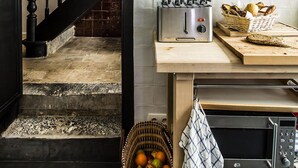 A kitchen with a black staircase, a toaster, a microwave, and shelves with dishes and jars. - La Maison Haute Guest House (Brussels)