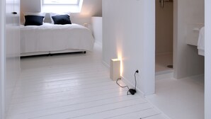 A bedroom with a bed, a skylight, and a bathroom with a shower. - La Maison Haute Guest House (Brussels)