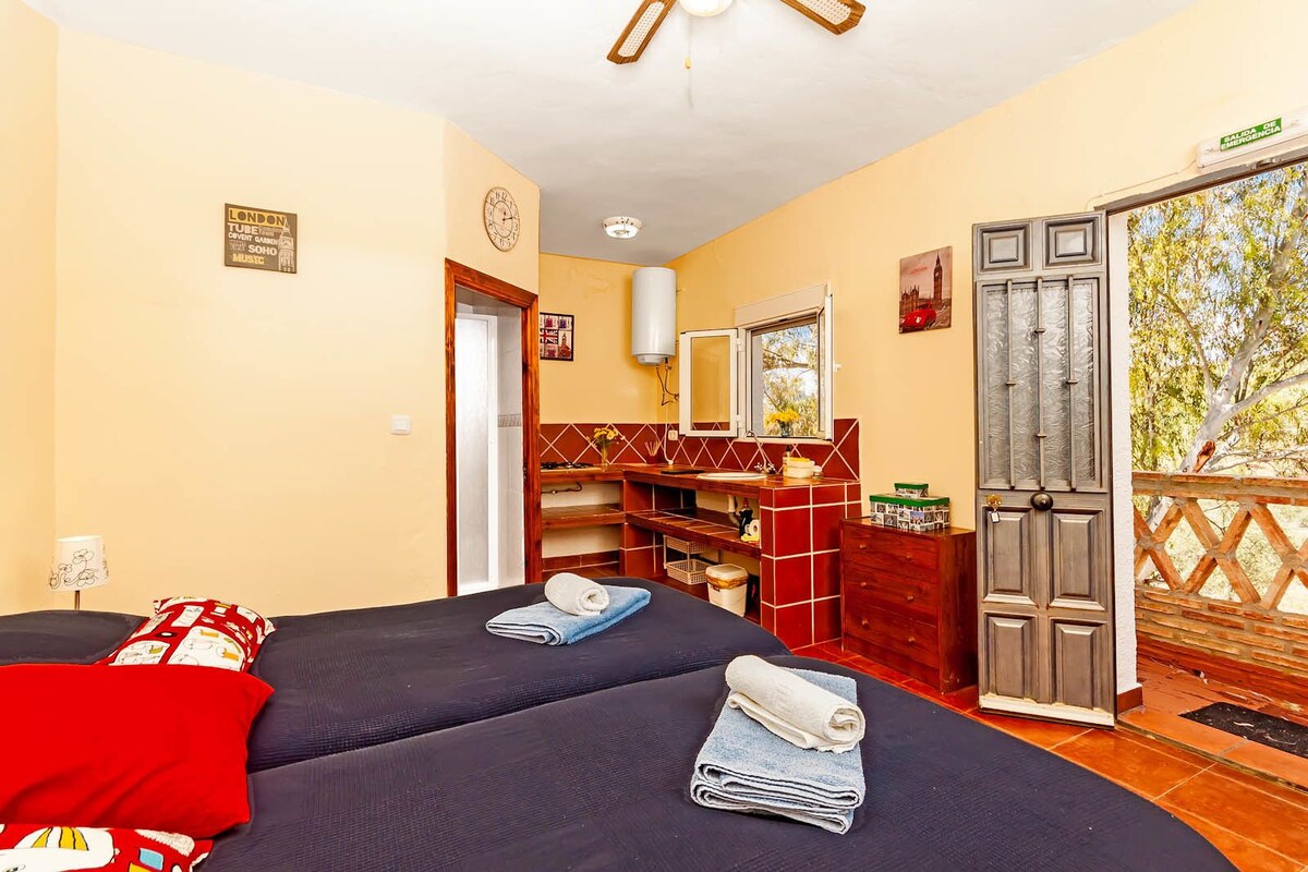 Une chambre d’hôtel avec deux lits, une salle de bain avec un miroir et une vue sur les arbres.