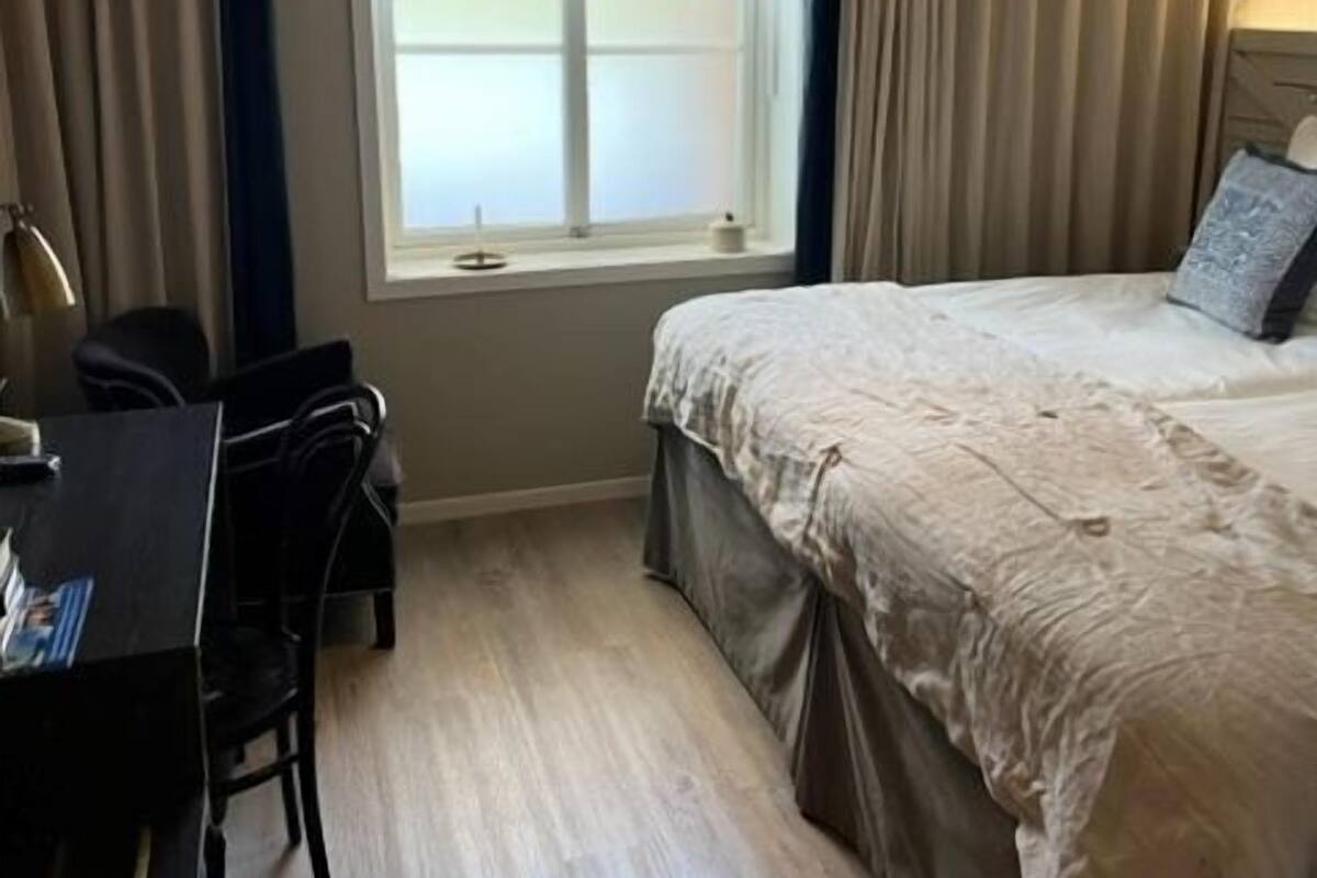 A hotel room with a bed, a desk, and a window.