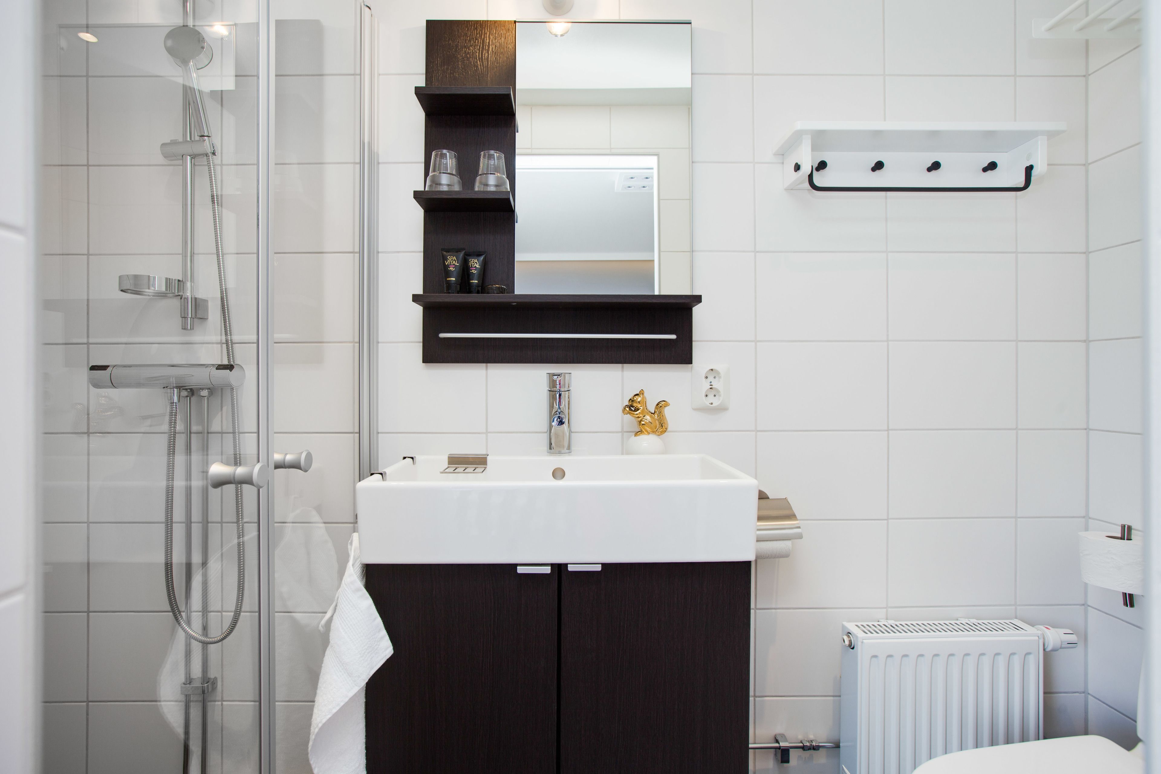 A modern bathroom with a shower, a sink, a mirror, and a towel rack.