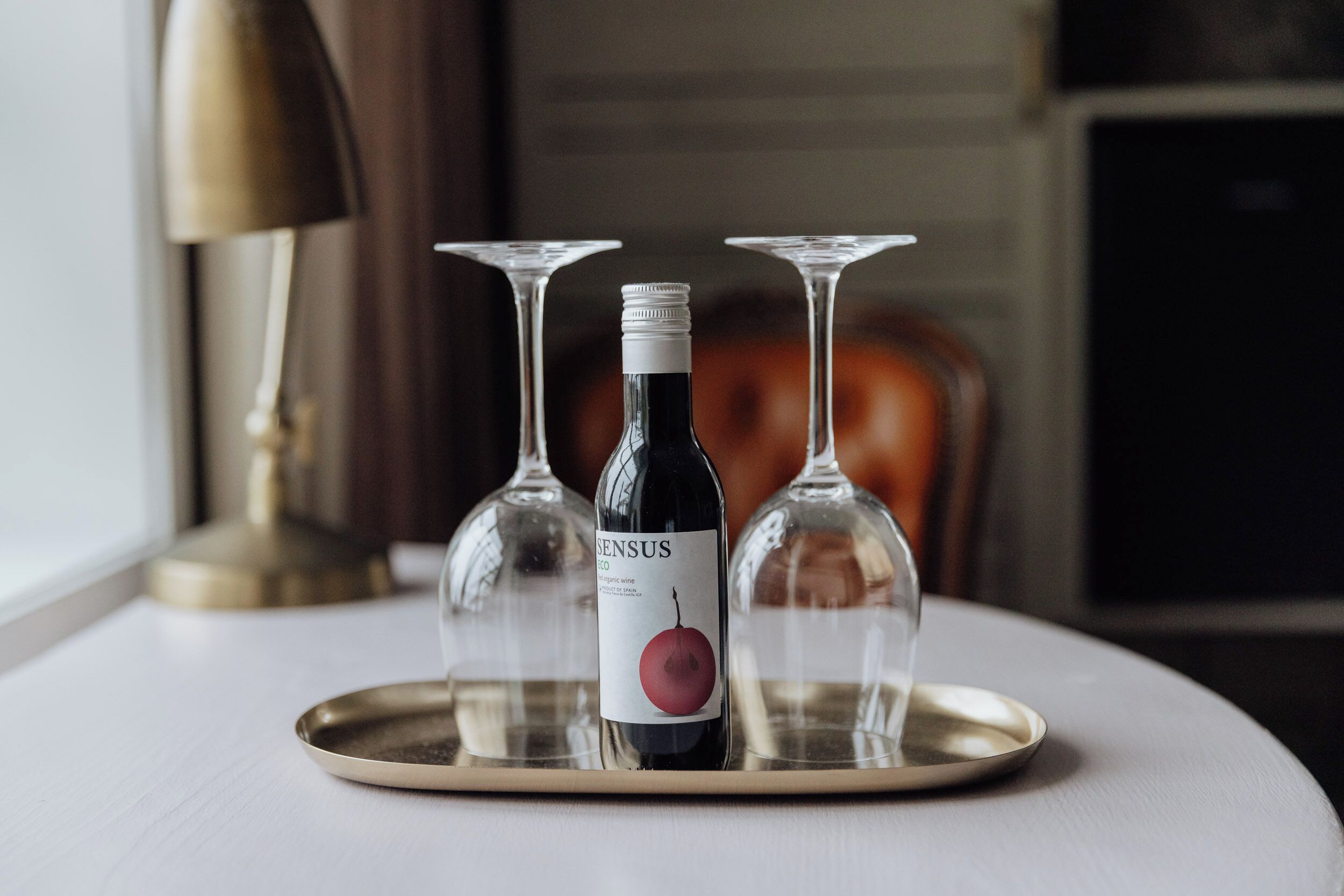Una bottiglia di vino su un vassoio con due bicchieri da vino vuoti.