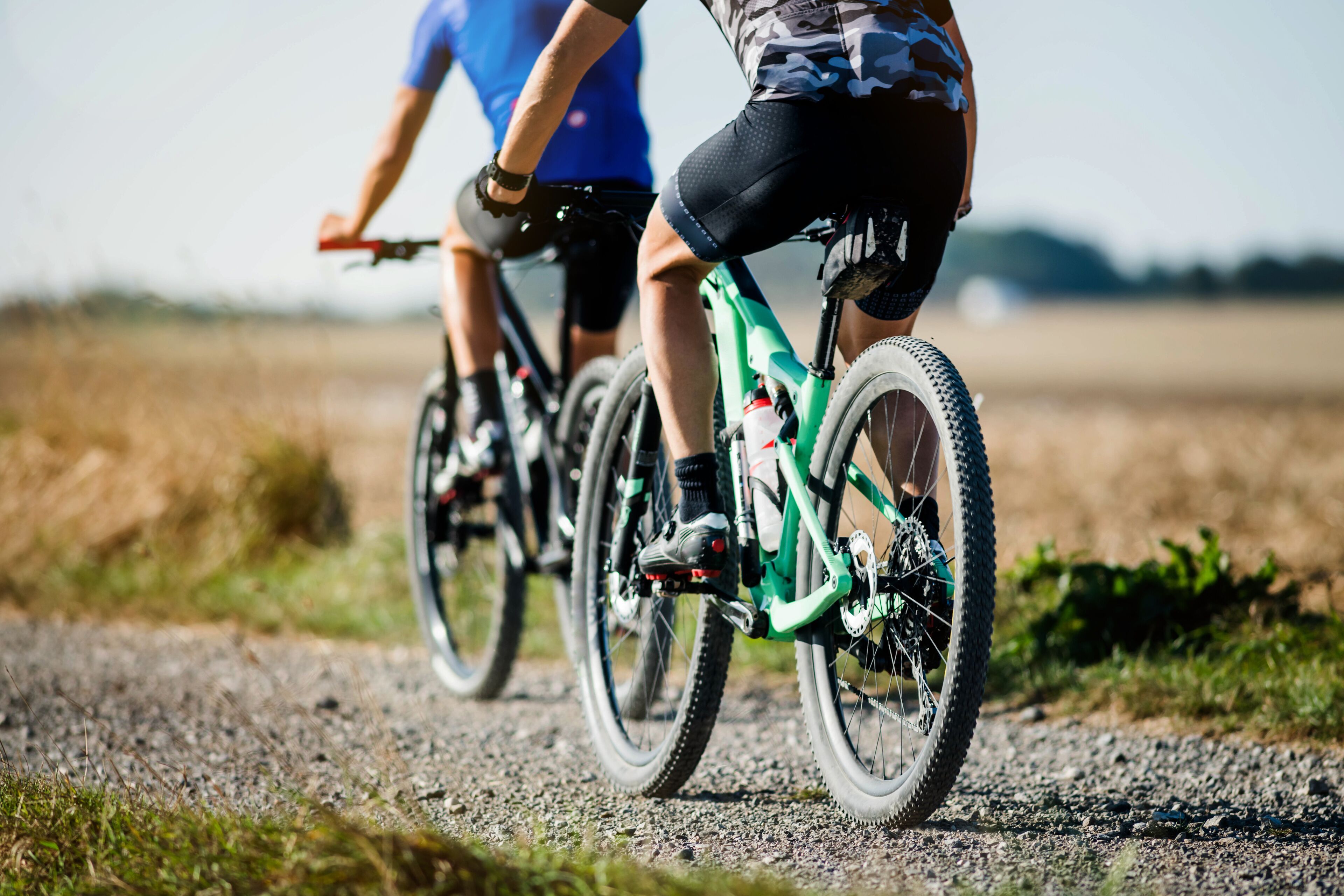 Two cyclists riding bicycles on a gravel path.