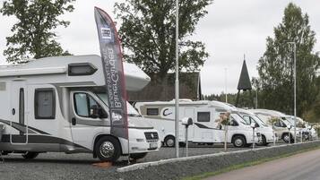 A row of RVs parked on a gravel lot with a road beside them.