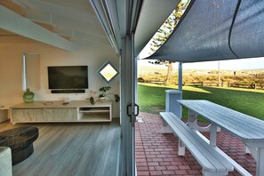 A modern living room with a TV, entertainment unit, and a view of a grassy field.