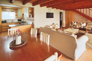 A spacious living area with a wooden dining table, white chairs, a sofa, and wicker chairs. - Fairway 2, Langebaan 6-sleeper (Langebaan)