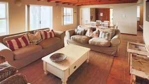 Ein gemütliches Wohnzimmer mit zwei Sofas, einem Couchtisch und Korbstühlen.