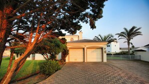 Ein Wohnhaus mit gepflasterter Auffahrt, Garage und gepflegtem Rasen.