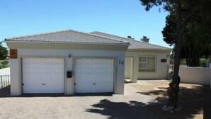 A two-story building with a garage and a small attached structure. - 6 Nendaz Self catering (Langebaan)