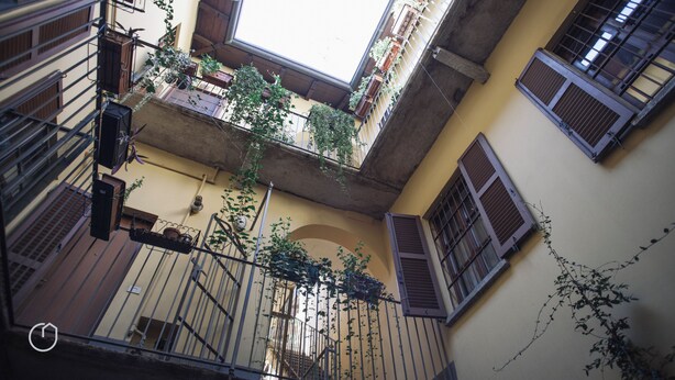A courtyard with multiple balconies, some with plants, and a view of the sky through the open space. - Italianway   - San Gottardo (Milan)