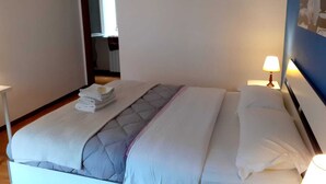 Une chambre d’hôtel avec un lit, une table de chevet avec une lampe et une porte donnant sur une autre pièce.