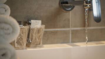 Un baño con una bañera, un perchero con toallas y un dispensador de jabón.