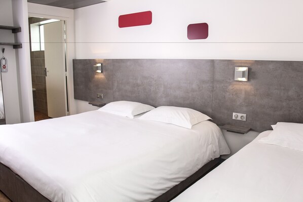 Una habitación de hotel moderna con una cama grande, una mesita de noche y una lámpara de pared.