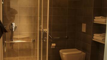 Un baño moderno con cabina de ducha de vidrio, inodoro y suelo de madera.