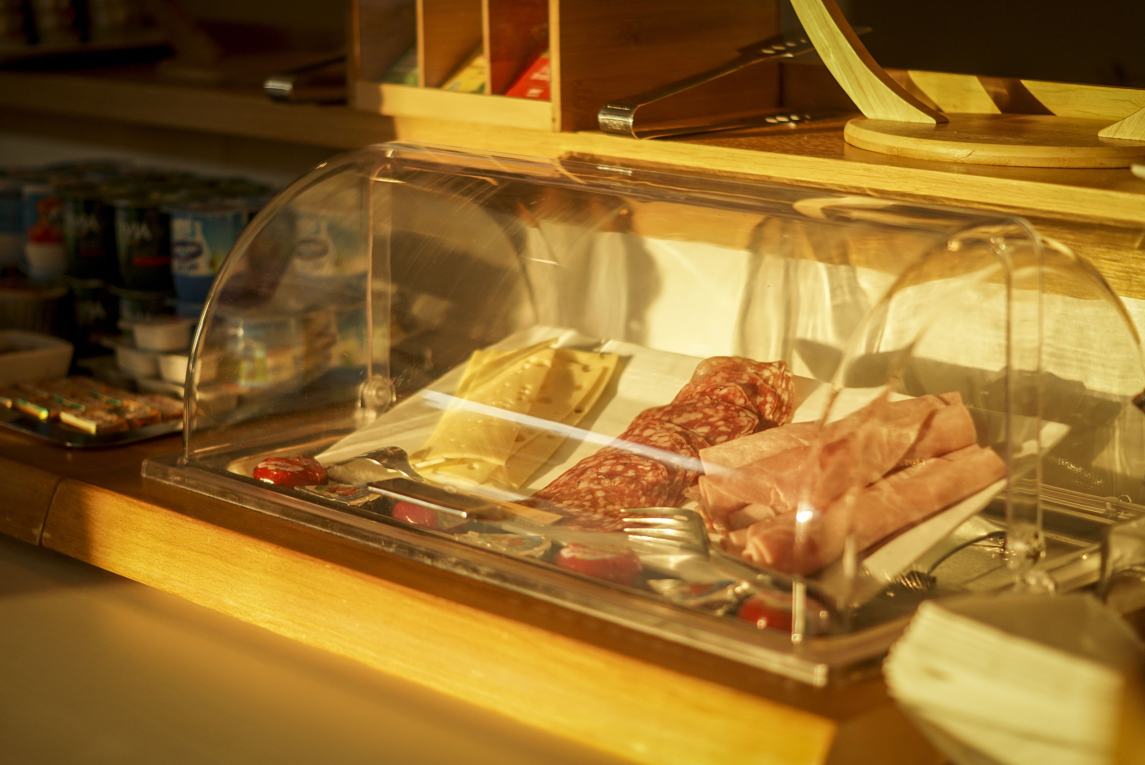 A deli counter with a glass display case containing various meats and cheeses.