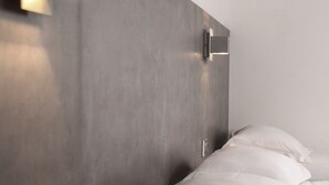 A modern hotel room with a large bed, a bedside table, and a wall-mounted light fixture. - H24 HOTEL Le Mans (Le Mans)