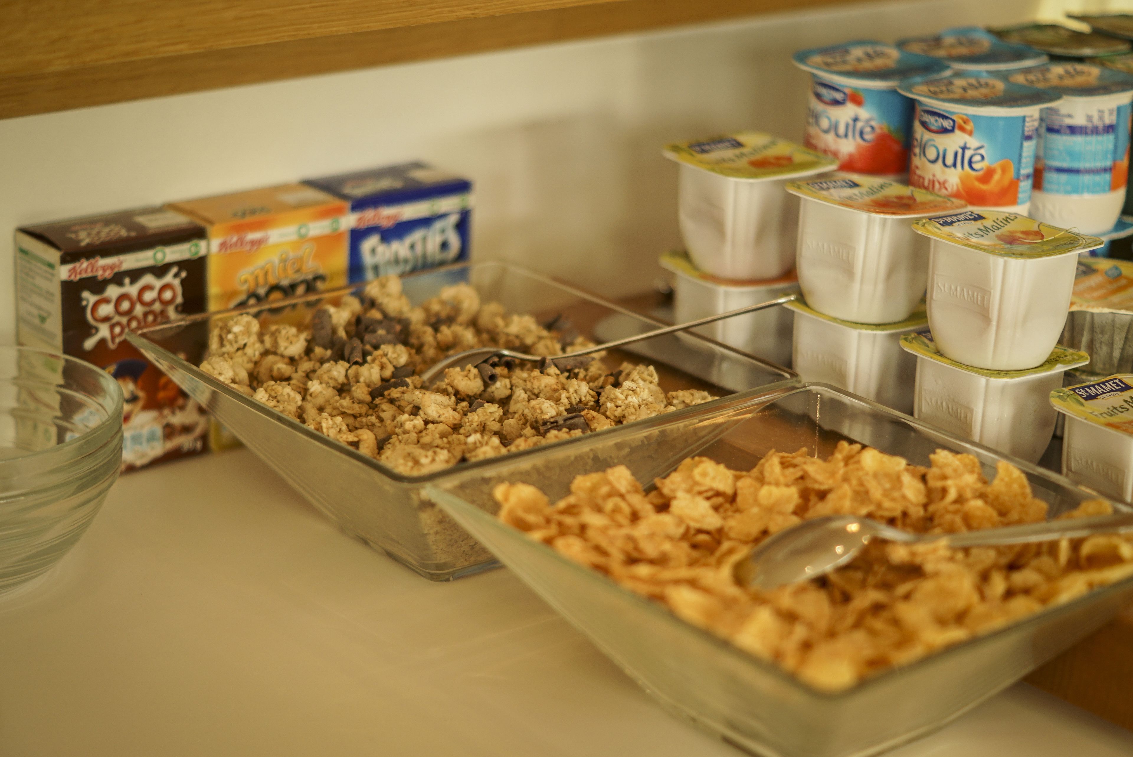 Un bufé de desayuno con diferentes cereales y recipientes de yogur.