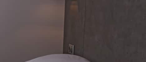 Un letto con biancheria bianca e una testiera con una lampada.