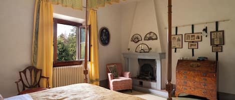 Un dormitorio tradicional con una cama con dosel, una chimenea y una colección de cuadros en la pared.